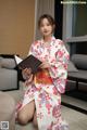 A woman in a kimono sitting on the floor holding a book.