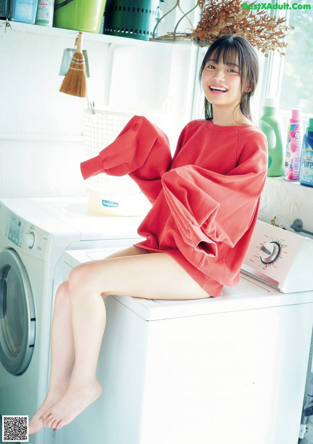 A woman sitting on top of a washing machine.